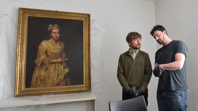 Visual arts teacher Ariel Bassano (left) stands next to a painting identified by Dutch newspaper AD as believed to be Portrait of a Lady by Italian Baroque portraitist Giuseppe Ghislandi, allegedly stolen by the Nazis from a Dutch Jewish art collector, as it is displayed at the Public Prosecutor's Office in Mar del Plata. Photo / AFP