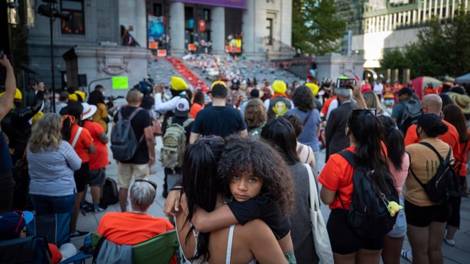 People listen during a ceremony and vigil for the 215 children whose remains were found buried at the former Kamloops Indian Residential School, in Vancouver on June 21. Photo / AP