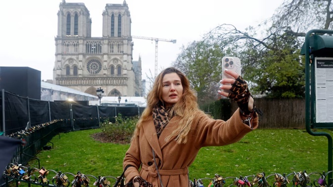 A tourist takes a selfie with Notre Dame Cathedral two days before its reopening to the public. Photo / Getty Images