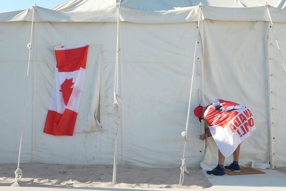 Canadian Modar Safar of Gilbert, Ontario ties closed his tent at a site in Al Khor, Qatar, Wednesday, Nov. 23, 2022. For scores of foreign soccer fans, the road to the World Cup in Doha starts every morning at a barren campsite in the middle of the desert. Visitors who found hotels in central Doha booked up or far beyond their budget have settled for the faraway, dust-blown tent village in Al Khor, where there are no locks on tents nor beers on draft. (AP Photo/Jon Gambrell)