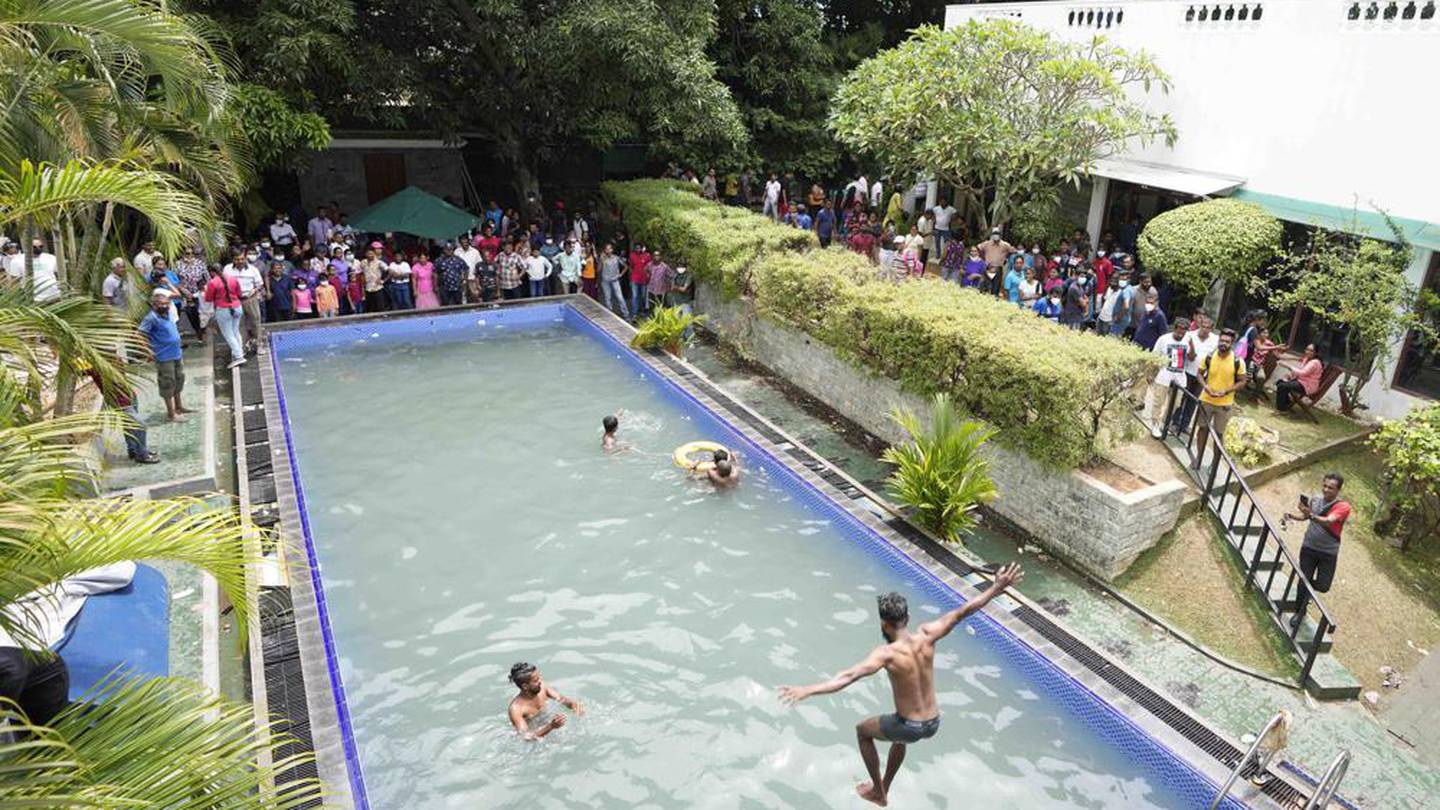 Protesters swim as onlookers wait at a swimming pool in president's official residence a day after it was stormed in Colombo, Sri Lanka. Photo / AP
