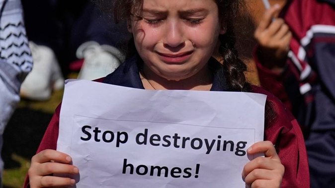 A girl weeps as she holds a placard during a protest against Israel's attack on the Gaza Strip, in front of the headquarters of the UN. Photo / AP