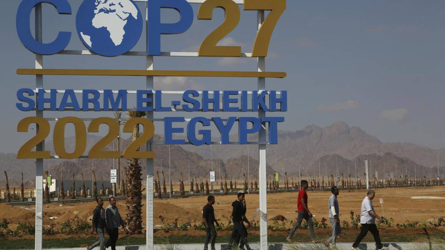 Workers walk past signage promoting this year’s United Nations global summit on climate change. Photo / AP