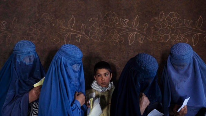 Afghan women wait to receive cash at a money distribution point organised by the World Food Program. Photo / AP