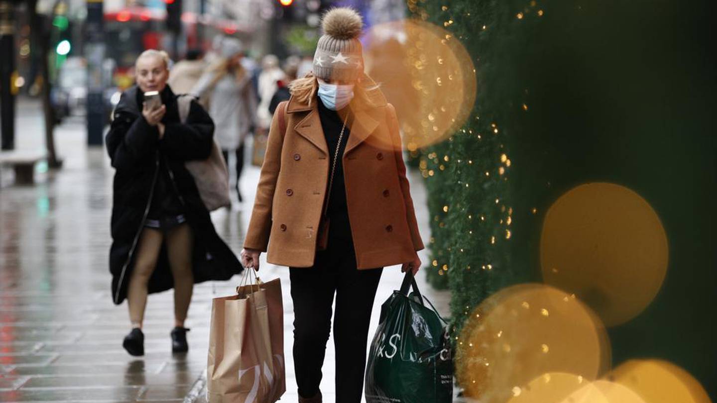 A woman wearing a face mask to guard against Covid-19 carries bags of shopping along Oxford St in London. Photo / AP