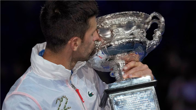 Novak Djokovic kisses the Norman Brookes Challenge Cup wearing a jacket bearing the number '22' - the number of grand slams he has now won. Photo / AP