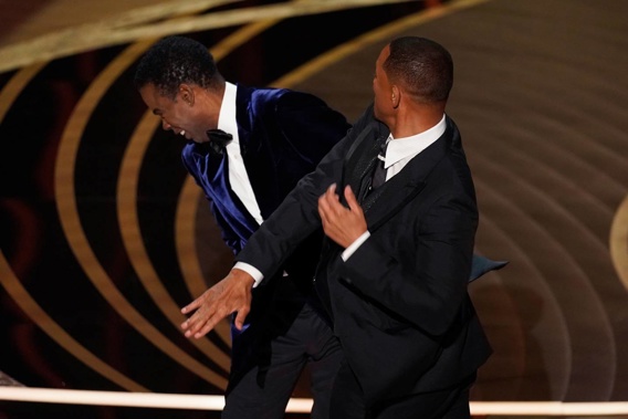 Will Smith hits presenter and actor Chris Rock on stage while presenting the award for best documentary feature at the Oscars. (Photo / AP)