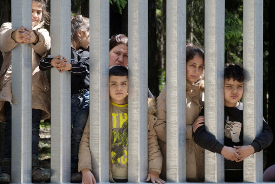 Members of a group of some 30 migrants seeking asylum are seen in Bialowieza, Poland, on Sunday, 28 May 2023 across a wall that Poland has built on its border with Belarus to stop massive migrant pressure. The group has remained stuck at the spot for three days, according to human rights activists. Photo / AP