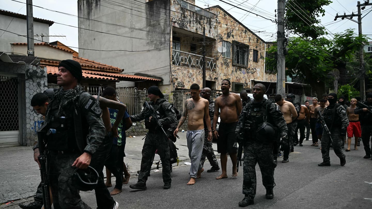 Police officers escort alleged criminals arrested during the operation at the Vila Cruzeiro favela, in the Penha complex, in Rio de Janeiro, Brazil, today. At least 2500 security forces agents took part in a raid to arrest drug-traffickers from the Comando Vermelho. Photo / Mauro Pimentel, AFP