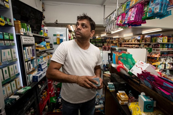 Uresh Patel owner of Kauriland Superette and Flower Shop stacks shelves a day after thieves ransacked it. Photo / Jason Oxenham