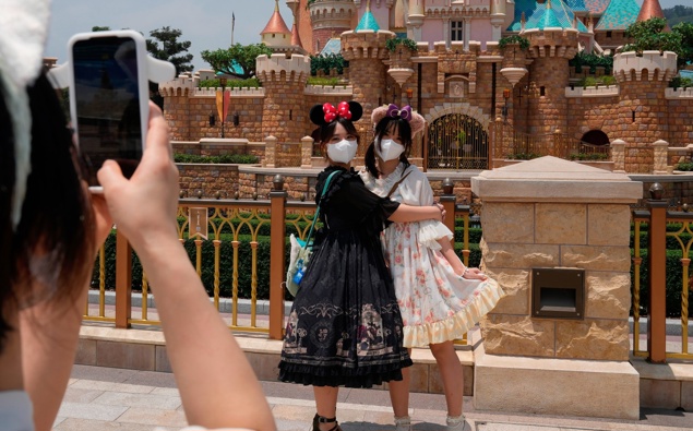 Visitors wearing face masks take photos at the Hong Kong Disneyland, Thursday, April 21, 2022. (Photo / AP)