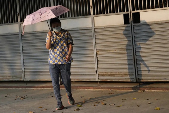A woman holds an umbrella to shelter from the sun in Bangkok, Thailand, Saturday, April 22, 2023. The authorities warned residents across Thailand to avoid outdoor activities due to extreme heat over the weekend. (AP Photo/Sakchai Lalit)