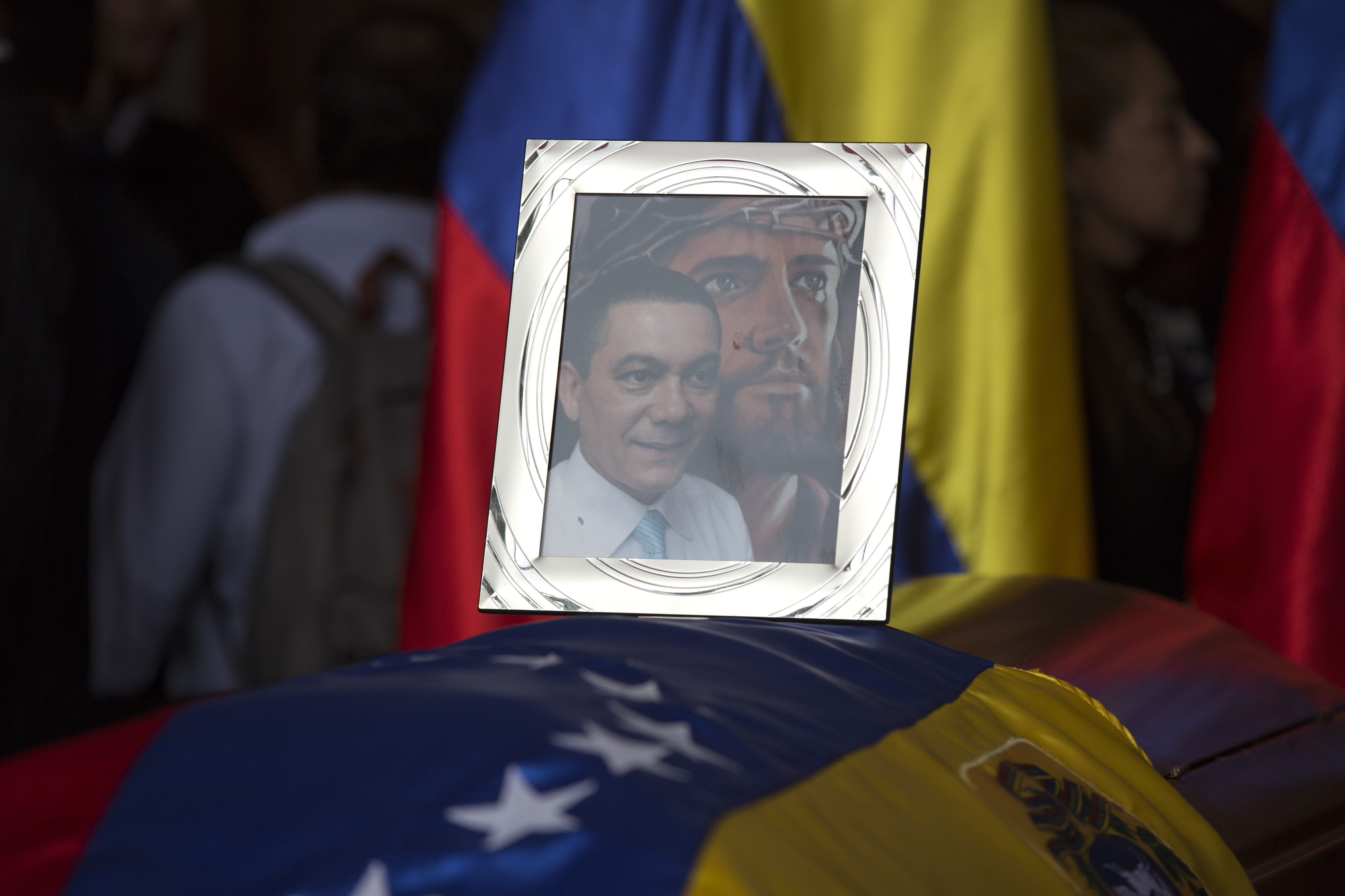 A framed portrait of opposition activist Fernando Alban shadowed by an image of Jesus Christ sits on the flag-draped casket containing his remains. Photo / AP