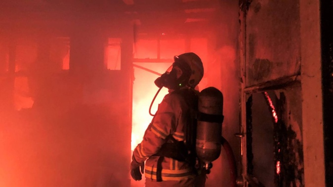 A volunteer firefighter at work inside the burning house on SH12 west of Kaikohe. Photo / supplied