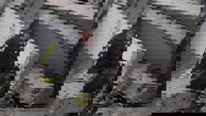 A rescue worker takes a pause as he sits on the debris at the scene where a woman was found dead after a Russian attack that heavily damaged a school. Photo / AP