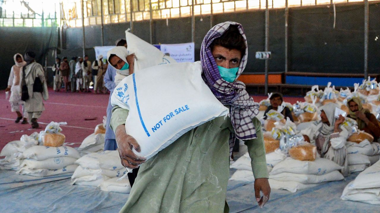 An Afghan man carries sacks of grains he received at a World Food Programme (WFP) facility in Kandahar on April 21, 2022.