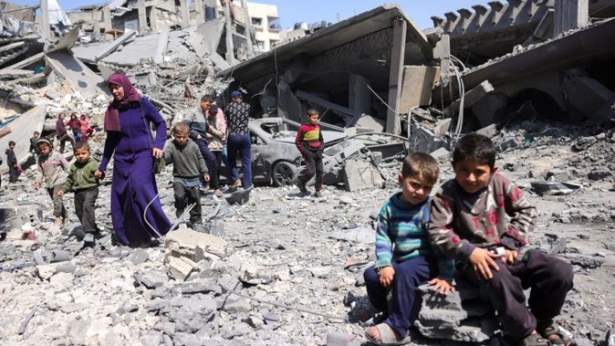 Children look on as people walk amid the rubble of a building destroyed in an overnight Israeli strike in Jabalia, in the northern Gaza Strip. Photo / AFP