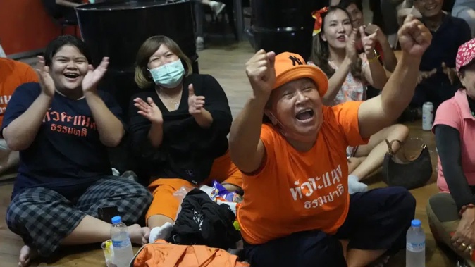 Supporters of Move Forward party cheer as they watch the counting of votes on television. Photo / AP