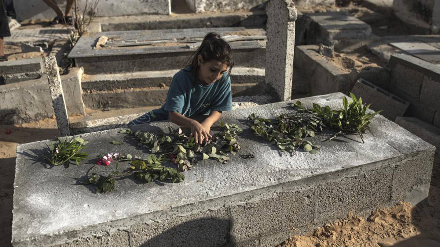 A Palestinian girl lays roses on the grave of one of the children of Nijim family at Al-Faluja cemetery in Jabalia. Photo / AP
