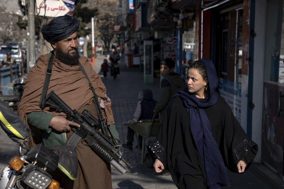 A Taliban fighter stands guard as a woman walks past in Kabul, Afghanistan. Photo / AP