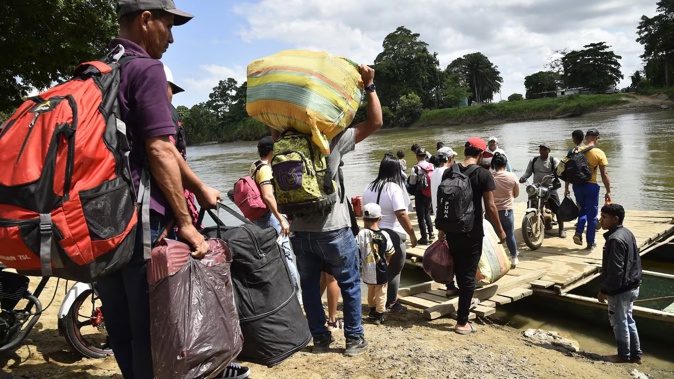 Displaced people board canoes to cross the Tarra River, which divides Colombia and Venezuela, in Tibu, Colombia on January 19. Photo / AFP
