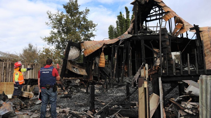 Fire investigator Craig Bain and a detective from Kaikohe police examine the ruins of the Omapere Rd home. (Photo / Peter de Graaf)