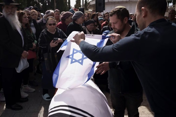 Relatives of Yitzhak Zeiger place an Israeli flag over his body during his funeral at a cemetery in Jerusalem, Israel. Photo / AP