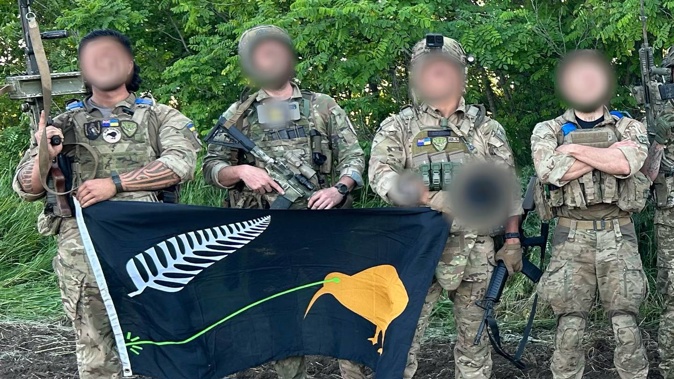 Two New Zealanders on the ground in Ukraine hold up the flag.