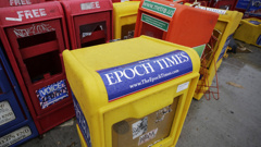 FILE - Plastic newspaper racks for The Epoch Times, The Village Voice and other newspapers stand along a Manhattan sidewalk, Wednesday, Nov. 27, 2013 in New York. The arrest of an executive at The Epoch Times in a money-laundering scheme this week has drawn attention to a media outlet that has largely lived in the shadows between its founding in 2000 and a transformation during the Trump administration. (AP Photo/Mark Lennihan, File)