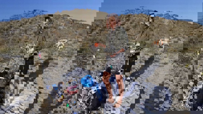 Papamoa Beach resident Sophie Lister with some of the rubbish found in the sane dunes after by beach partygoers on November 26. Photo / Bruce Hutchinson