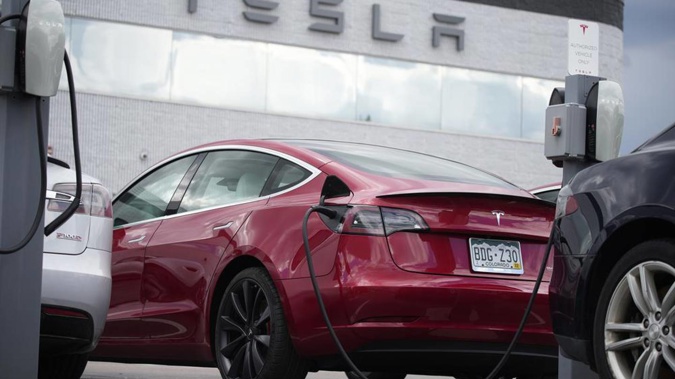 A 2021 Model 3 sedan is connected to a charger at a Tesla dealership. Photo / AP