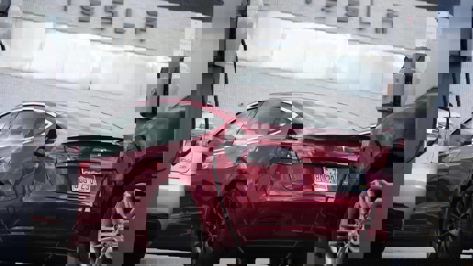 A 2021 Model 3 sedan is connected to a charger at a Tesla dealership. Photo / AP