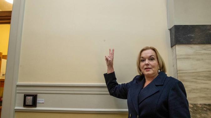 National leader Judith Collins mimics Churchill's V for Victory sign, beside the wall where his portrait once hung. (Photo / Mark Mitchell)