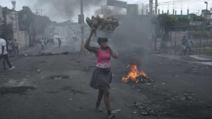 A street vendor walks past a barricade set up by demonstrators to protest against fuel price hikes and to demand that Haitian Prime Minister Ariel Henry step down. Photo / AP