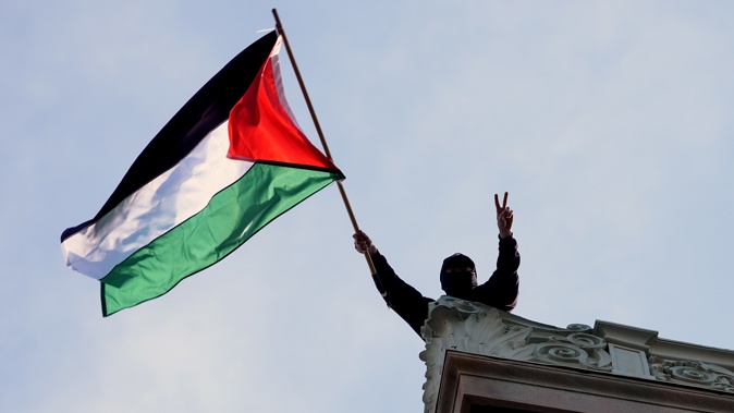 A student protester waves a Palestinian flag above Hamilton Hall on the campus of Columbia University, Tuesday, April 30, 2024, in New York. Photo / Pool | Mary Altaffer