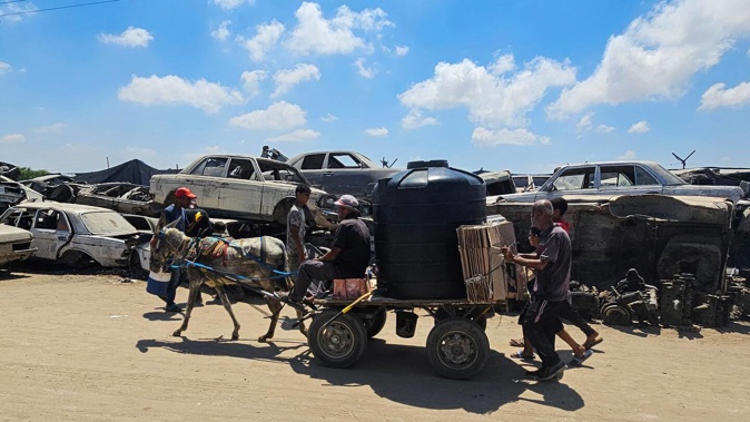 Palestinians use a donkey and cart for transport as dilapidated cars are piled up in a junkyard in the Mawasi area of Rafah due to a scarcity of fuel in the Israel-besieged Gaza Strip. Photo / AFP