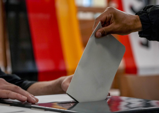 A man casts his ballot for the German elections in a polling station in Berlin, Germany, Sunday, Sept. 26, 2021. In background the German national flag. (Photo / AP)