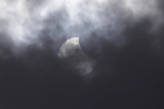 A partial solar eclipse is seen through the cloud over Jakarta, Indonesia, Thursday, April 20, 2023. A rare solar eclipse will cross over remote parts of Australia, Indonesia and East Timor on Thursday.