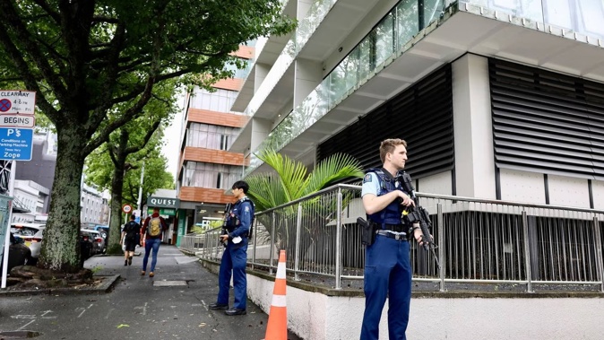 Armed police stand out the front of a building on Wellesley in Auckland's city centre. Photo / Jed Bradley