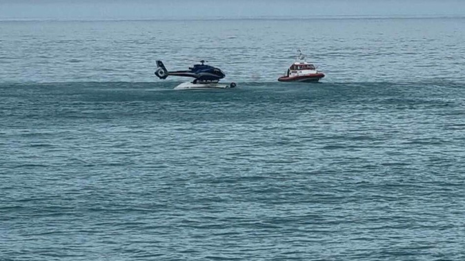 A helicopter hovered above the upturned boat to rescue those clinging to the hull. Photo / Supplied