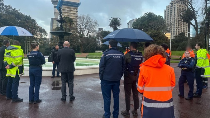 Around 30 people, mostly officers and council workers in uniform, have gathered around the fountain at Albert Park.