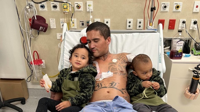 West Auckland scaffolder Jahden Nelson in his Middlemore Hospital bed with daughter Valley Rose, 3, on the left, and son Kaiser, 2. Photo / Supplied