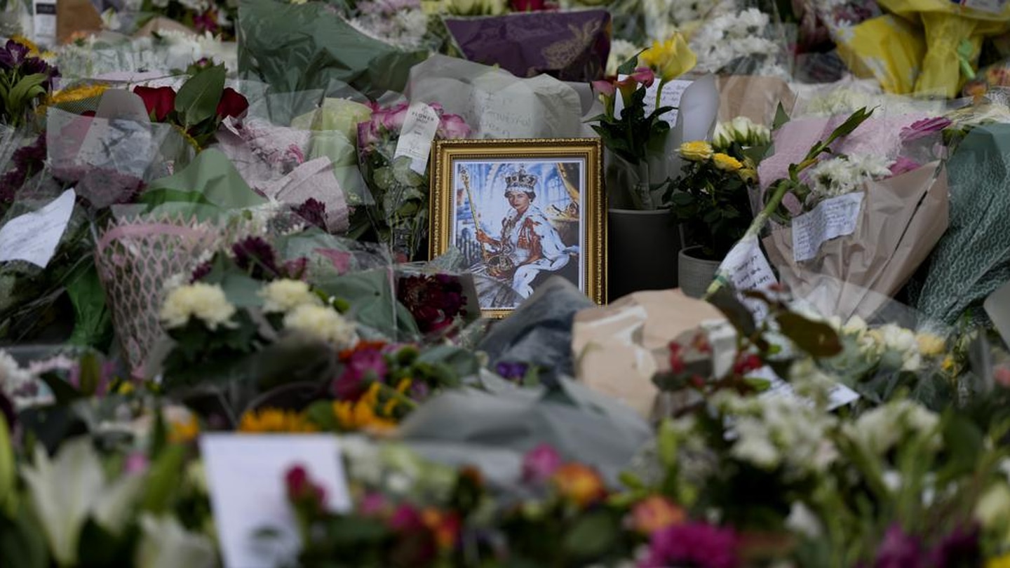 A portrait of Queen Elizabeth II sits amidst floral tributes and notes outside the gates of Windsor Castle. Photo / AP