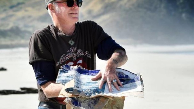 Broad Bay resident Barrie Mangan with some of the disintegrated Sealord boxes that washed up on Allans Beach. Photo / Peter McIntosh