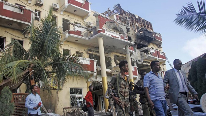 Security forces and others walk in front of the damaged Hayat Hotel in the capital Mogadishu, Somalia. Photo / AP