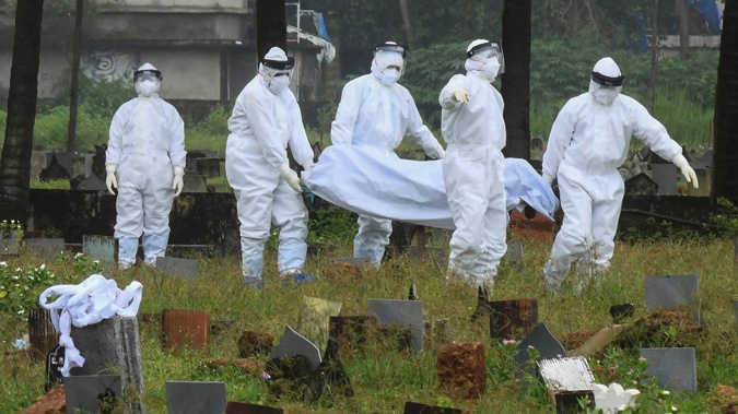 People in protective suits prepare to cremate the body of a 12-year-old boy who died of the Nipah virus in Kozhikode, Kerala, in India. (Photo / AP)
