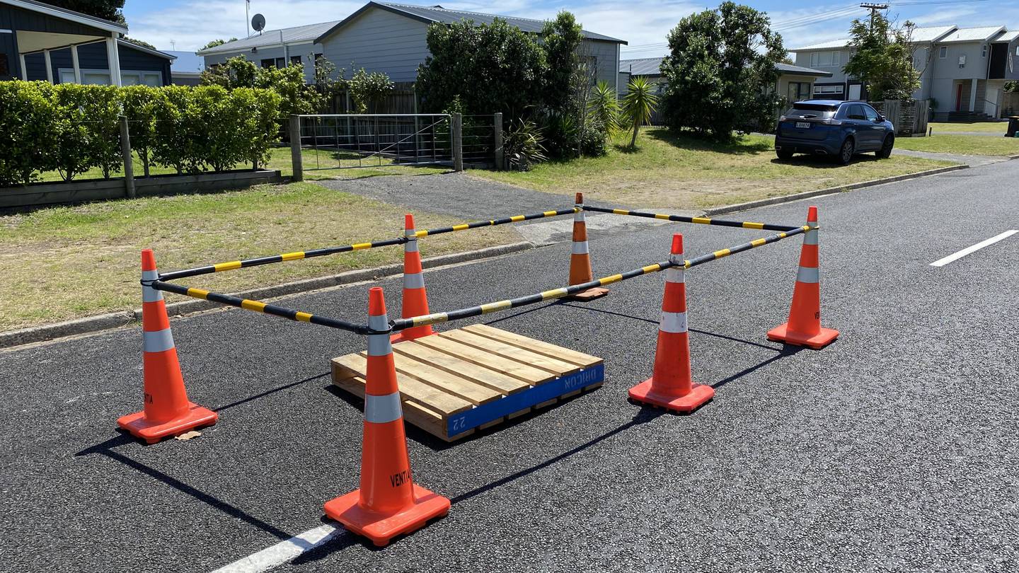 Cones and a pallet mark the area where a sinkhole was found in a residential Whangamata street. Photo / Jim Birchall