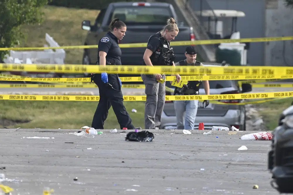 Investigators look over the scene of an overnight mass shooting at a strip mall in Willowbrook, Ill., Sunday, June 18, 2023.