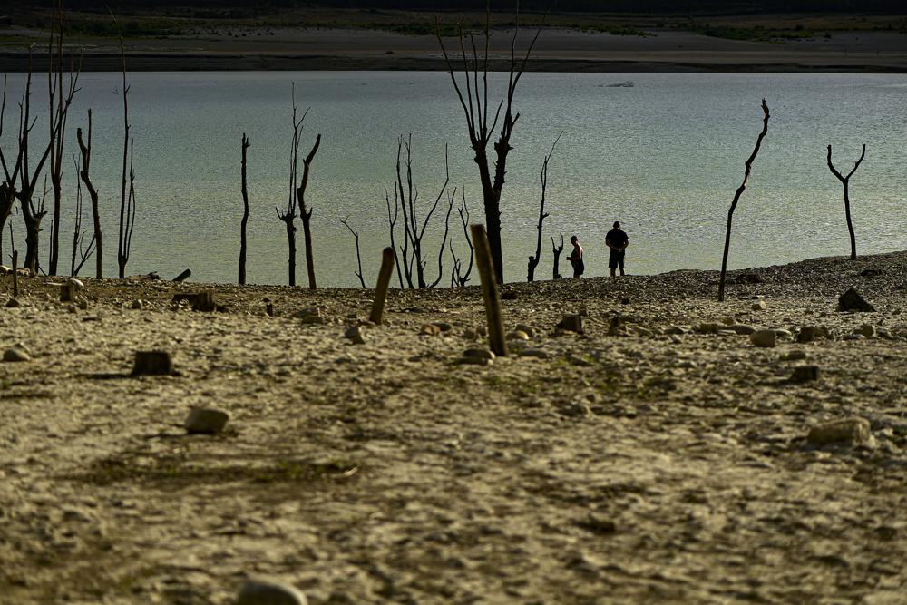 People walk close to the border at Yesa's reservoir affected by drought, on a sunny summer day in Yesa, around 55 kilometers (34,17 miles), from Pamplona, northern Spain, Sept. 14, 2022. Widespread drought that dried up large parts of Europe, the United States and China this past summer was made 20 times more likely by climate change, according to a new study. (AP Photo/Alvaro Barrientos)