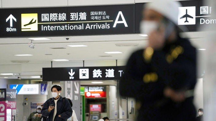 Men hold their phones as they stand by an arrival gate for international flights at the Narita International Airport in Narita, east of Tokyo, Thursday, Dec. 2, 2021. (Photo / AP)